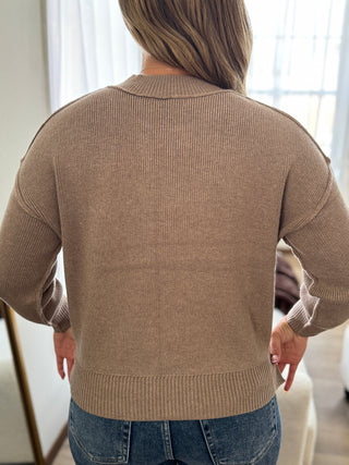Person wearing a beige sweater with a blurred background