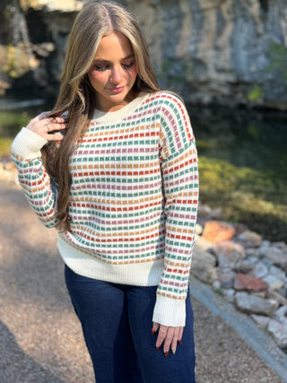 Cream grid knit sweater with green, red and gold stripes and jeans | V-Rae's Boutique