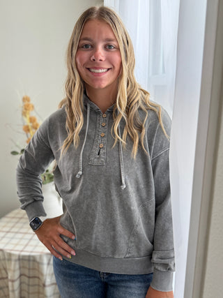 Person wearing a gray hoodie with buttons indoors