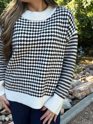 Close-up of a houndstooth sweater with striped sleeves | V-Rae's Boutique