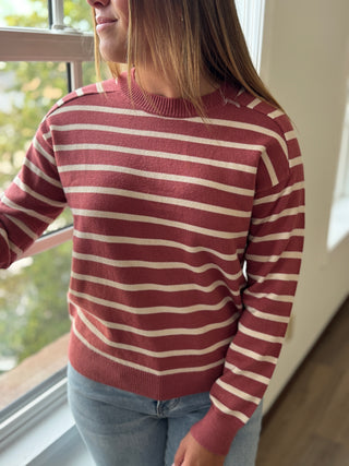 Person wearing a red and white striped sweater by a window