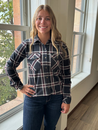 Person wearing a plaid shirt and jeans standing in front of a window.