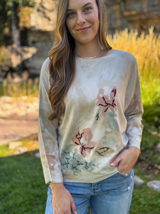 Woman in a cream batwing knit sweater with watercolor floral print | V-Rae's Boutique