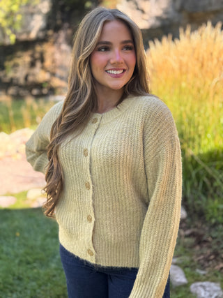 Woman in a light olive chunky ribbed knit cardigan with buttons | V-Rae's Boutique