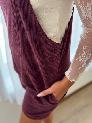Person wearing a burgundy knitted vest over a white lace top.