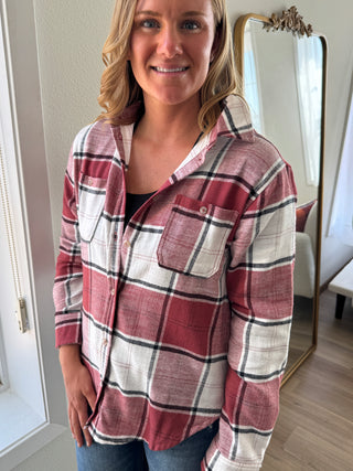 Person wearing a red and white plaid shirt standing in front of a mirror.