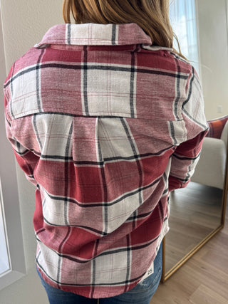 Person wearing a red and white plaid shirt with a blurred background