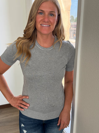 Woman wearing a gray t-shirt and blue jeans indoors
