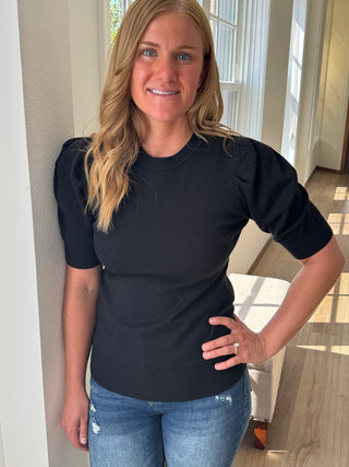 Woman wearing a black top and blue jeans indoors