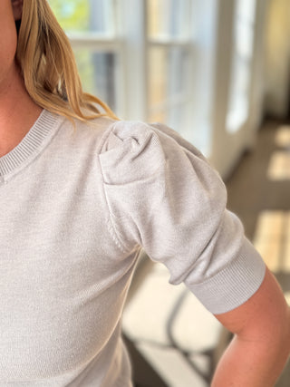 Light gray sweater with puff sleeves worn by a person indoors.