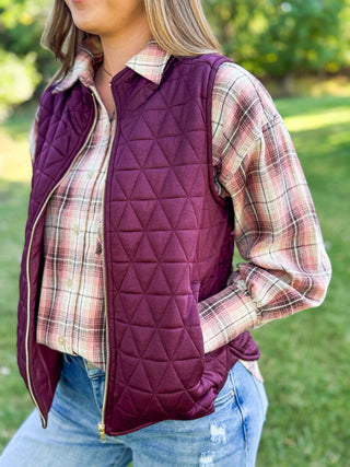 Side view of a wine quilted puffer vest worn open over a plaid flannel | V-Rae's Boutique
