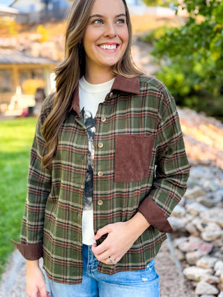 Woman in a green plaid flannel with brown corduroy pocket and cuffs over a graphic tee | V-Rae's Boutique