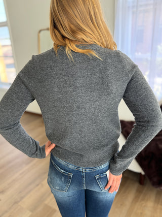 Person wearing a gray sweater and blue jeans in an indoor setting