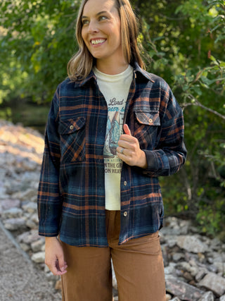 Woman in a navy and orange plaid flannel shacket over a graphic tee | V-Rae's Boutique