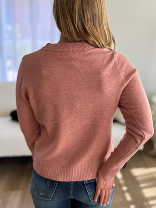 Person wearing a pink sweater in an indoor setting