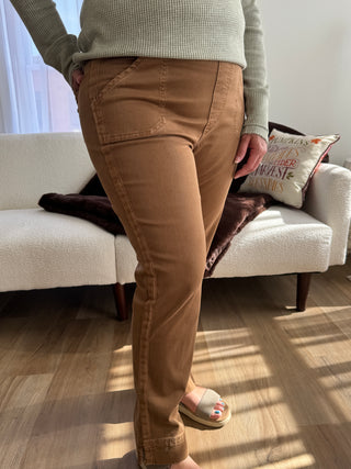 Person wearing brown pants sitting on a white couch with a neutral background