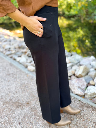 Side view of black scuba high waist pants with a hand in the pocket | V-Rae's Boutique