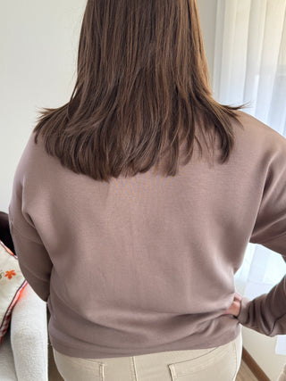 Person wearing a beige hoodie and pants in an indoor setting