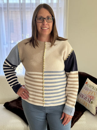 Woman wearing a striped sweater standing in a living room.