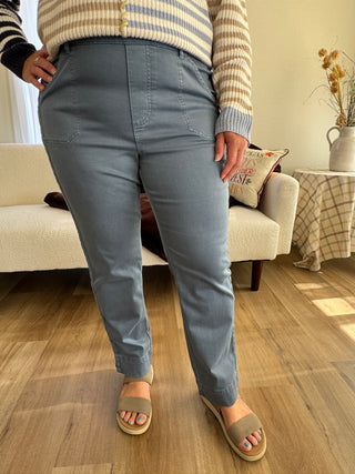 Person wearing blue pants and sandals sitting on a couch with a wooden floor.