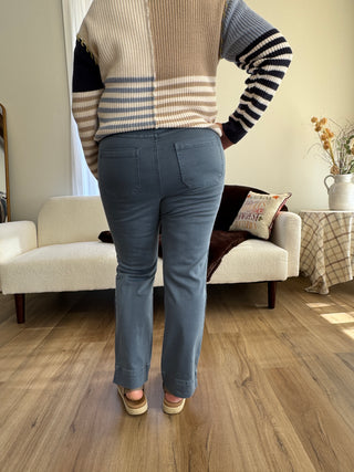 Person wearing a striped sweater and blue jeans lounging on a couch in a living room.