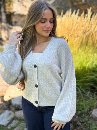 Woman in a heather gray V-neck cardigan with balloon sleeves and dark buttons | V-Rae's Boutique