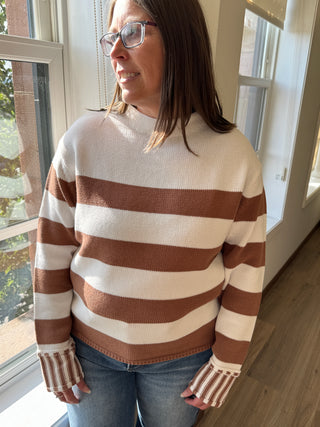 Person wearing a brown and beige striped sweater indoors.