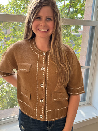 Woman wearing a brown sweater with white buttons indoors