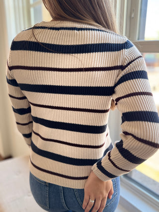 Back of Lady looking out window wearing a stripe pullover sweater.