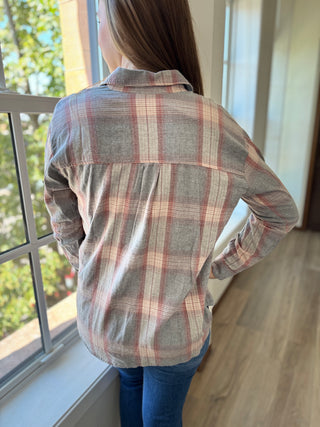 Back of Lady standing by window wearing a grey plaid flannel over a henley shirt.