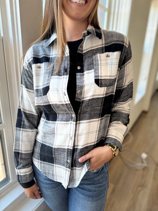 Woman wearing a white and black plaid shirt with a plain background