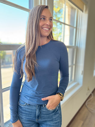 Lady standing wearing a blue long sleeve top.