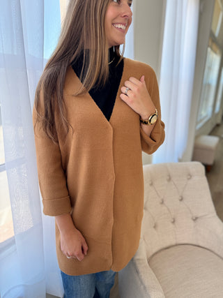 Lady standing next to chair wearing a mocha long length cardigan.