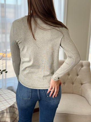 Back of Lady standing featuring an olive button up henley top.