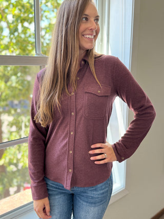 Lady standing by window wearing a wine button up flannel.