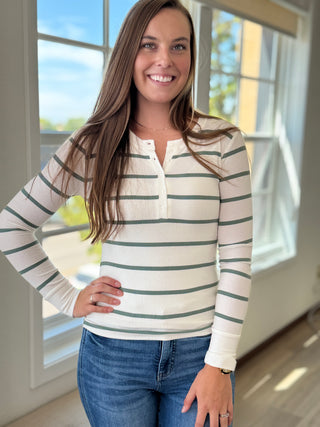 Lady wearing a spruce and white colored henley button up top.