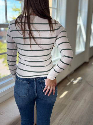 Back of lady wearing a spruce and white colored henley button up top.