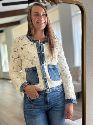 Woman wearing a cream jacket with denim accents in front of a mirror.