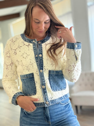 Woman wearing a cream lace jacket with denim accents indoors