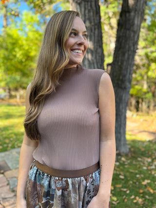 Woman in a mocha pleated sleeveless shell top with floral skirt | V-Rae's Boutique