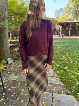 Woman in a plum exposed seam cropped sweater with plaid midi skirt | V-Rae's Boutique