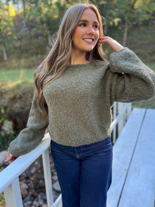 Woman in an olive fuzzy boat neck sweater with dark jeans | V-Rae's Boutique