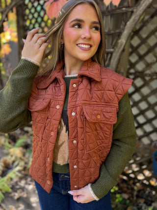 Woman in a rust quilted snap-front utility vest over a green sweater | V-Rae's Boutique