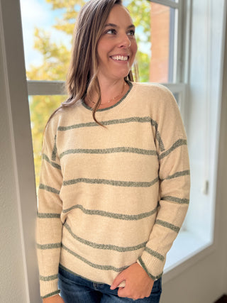 Woman wearing a beige and green striped sweater indoors.