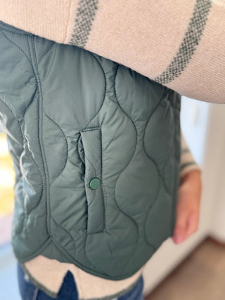 Green quilted jacket with a blurred background