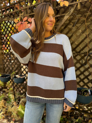 Woman in a brown and light blue wide stripe crewneck sweater | V-Rae's Boutique
