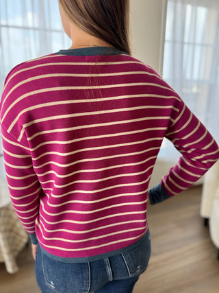 Person wearing a maroon and beige striped sweater in a home setting
