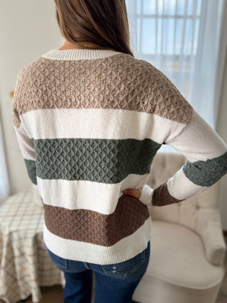 Person wearing a striped sweater with a neutral color palette indoors.
