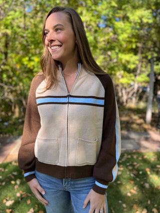 Woman in a cream and brown retro stripe zip-up sweater | V-Rae's Boutique