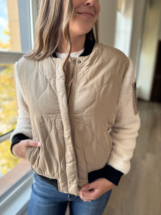 Woman wearing a beige quilted vest indoors